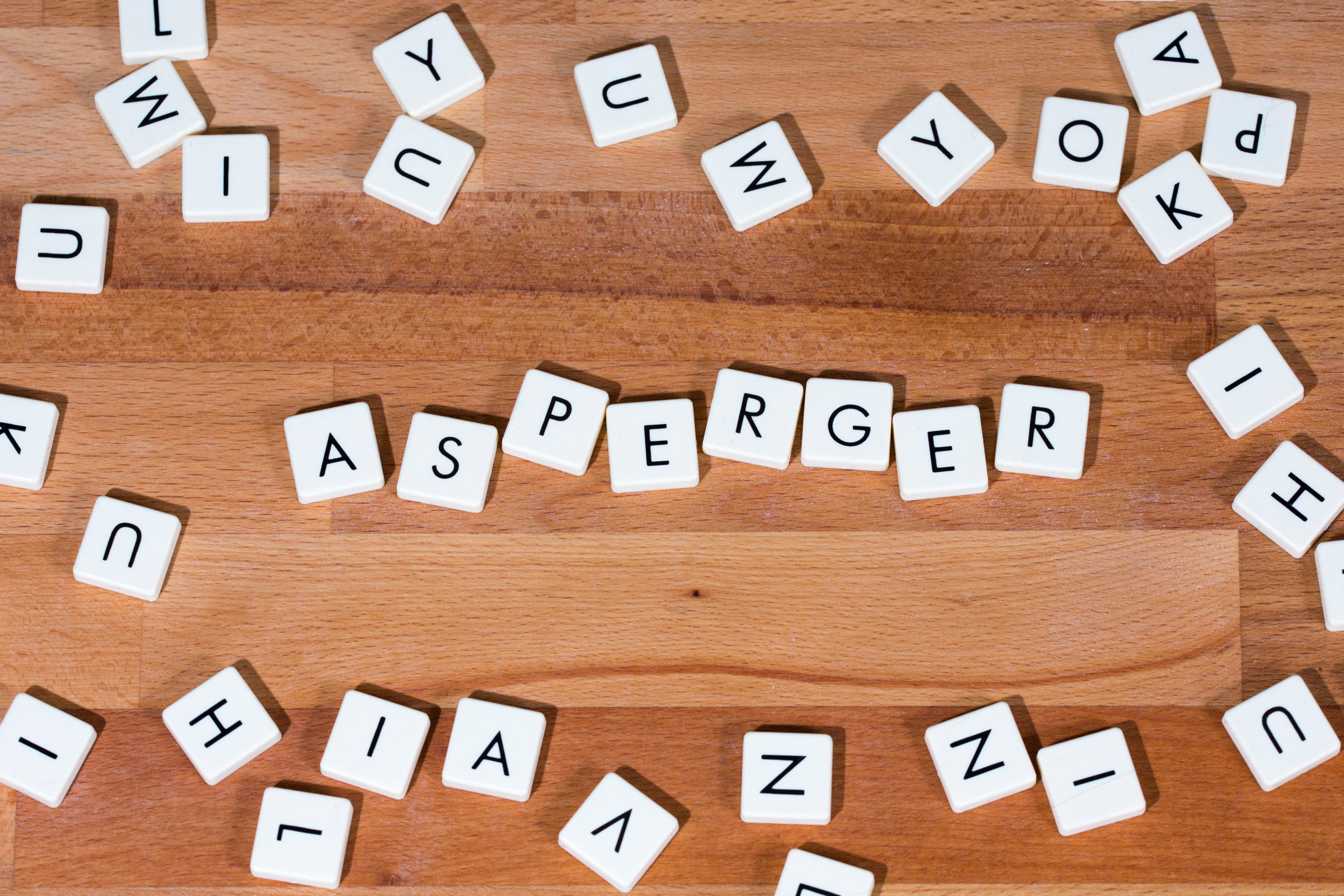 Asperger text on a wooden surface surrounded by letters. Asperge