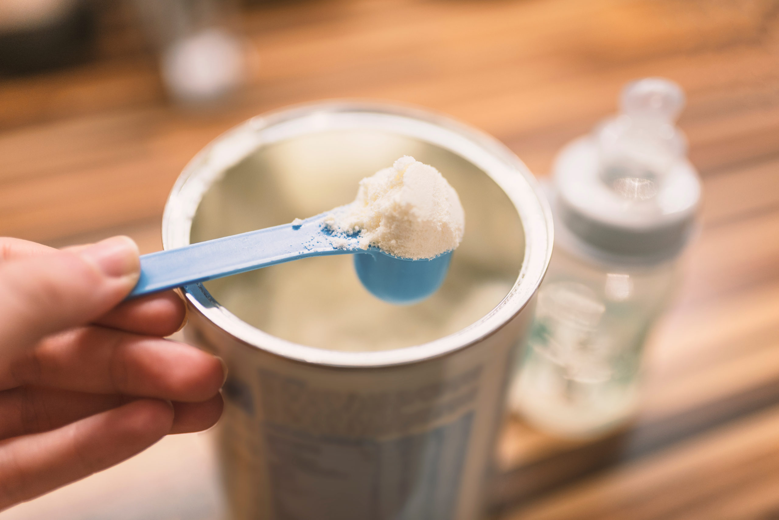 Powder milk for baby and blue spoon on light background close-up