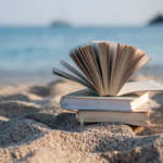 Découvrez les meilleurs livres à emporter à la plage cet été ! Collection de livres posée sur une serviette de plage avec une vue sur l'océan