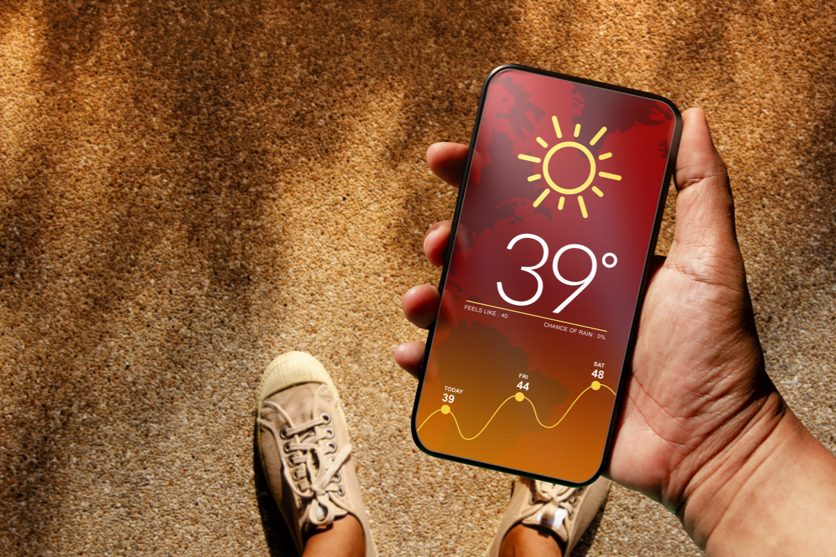 Personne consultant une application météo sur son smartphone avec un fond de ciel nuageux