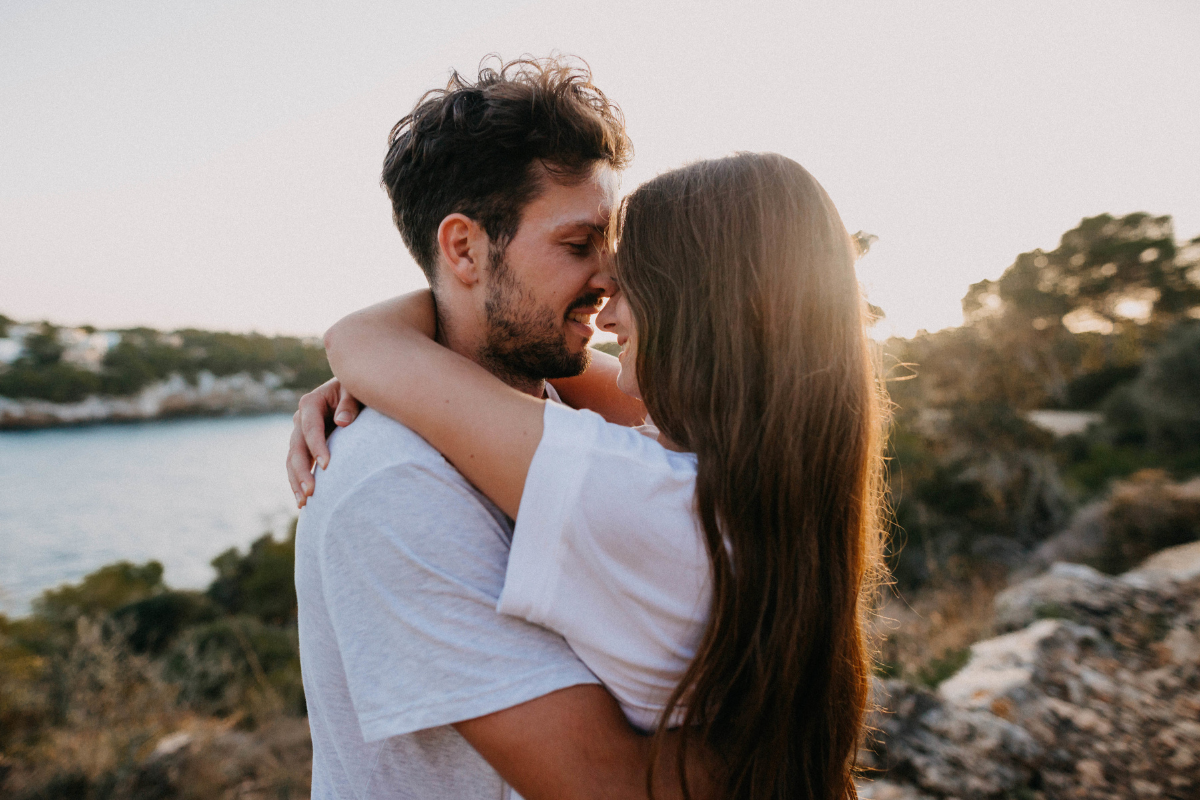 Un couple en train de discuter, l'homme chuchotant des mots doux à l'oreille de la femme qui sourit