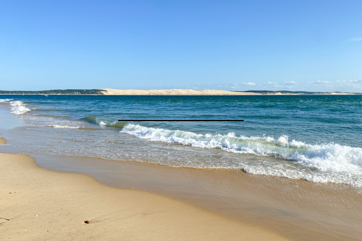 Vue panoramique d'une plage idyllique au Cap Ferret avec sable fin et océan bleu