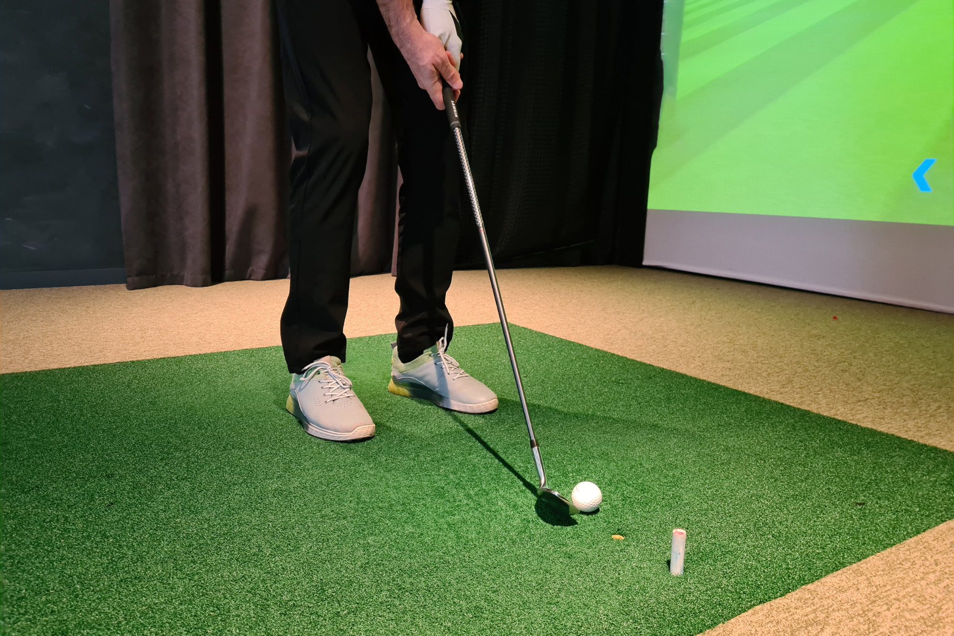 Simulateur de golf installé dans une maison, avec un joueur en pleine action